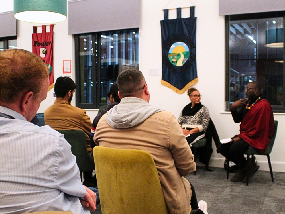 Rows of chairs filled with a keen audience face towards a panel of speakers at the front of a bright room